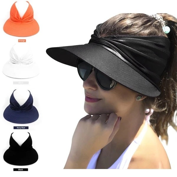 A smiling woman wearing sunglasses models the True Adult & Big Kids Wide Brim UV Protect Sun Visor Cap in black, featuring a stylish twisted knot design at the front for sun protection. The image also highlights this lightweight cap in four additional colors: orange, white, navy blue, and black. As she touches her chin, you can see the effortless elegance of the visor hat.