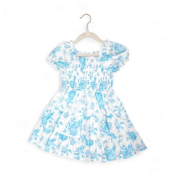 White dress with blue floral pattern on a hanger against a white background