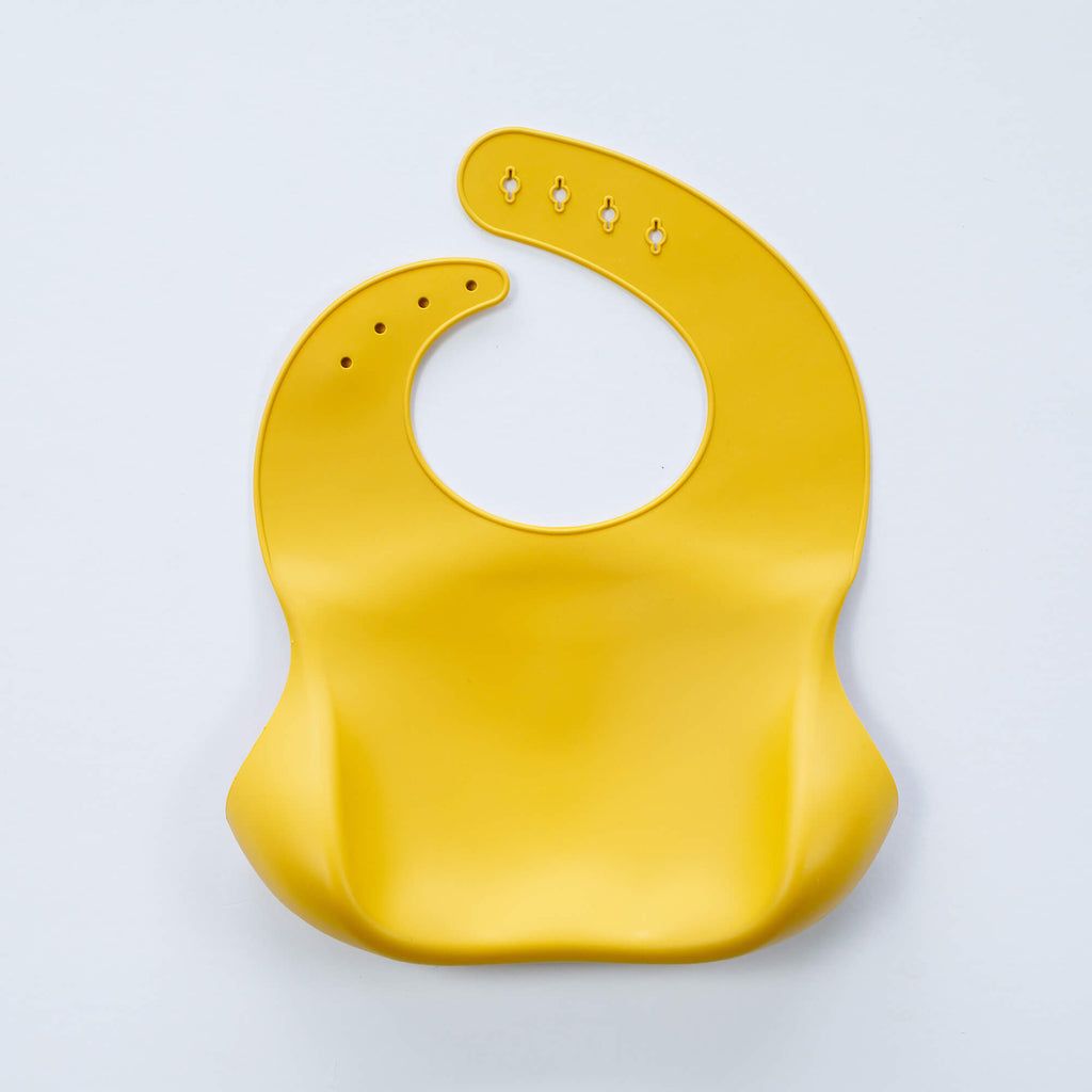 A yellow, BPA-free Silicone Bucket Bib with an adjustable neck strap featuring snap buttons. The bib has a scoop at the bottom to catch food.