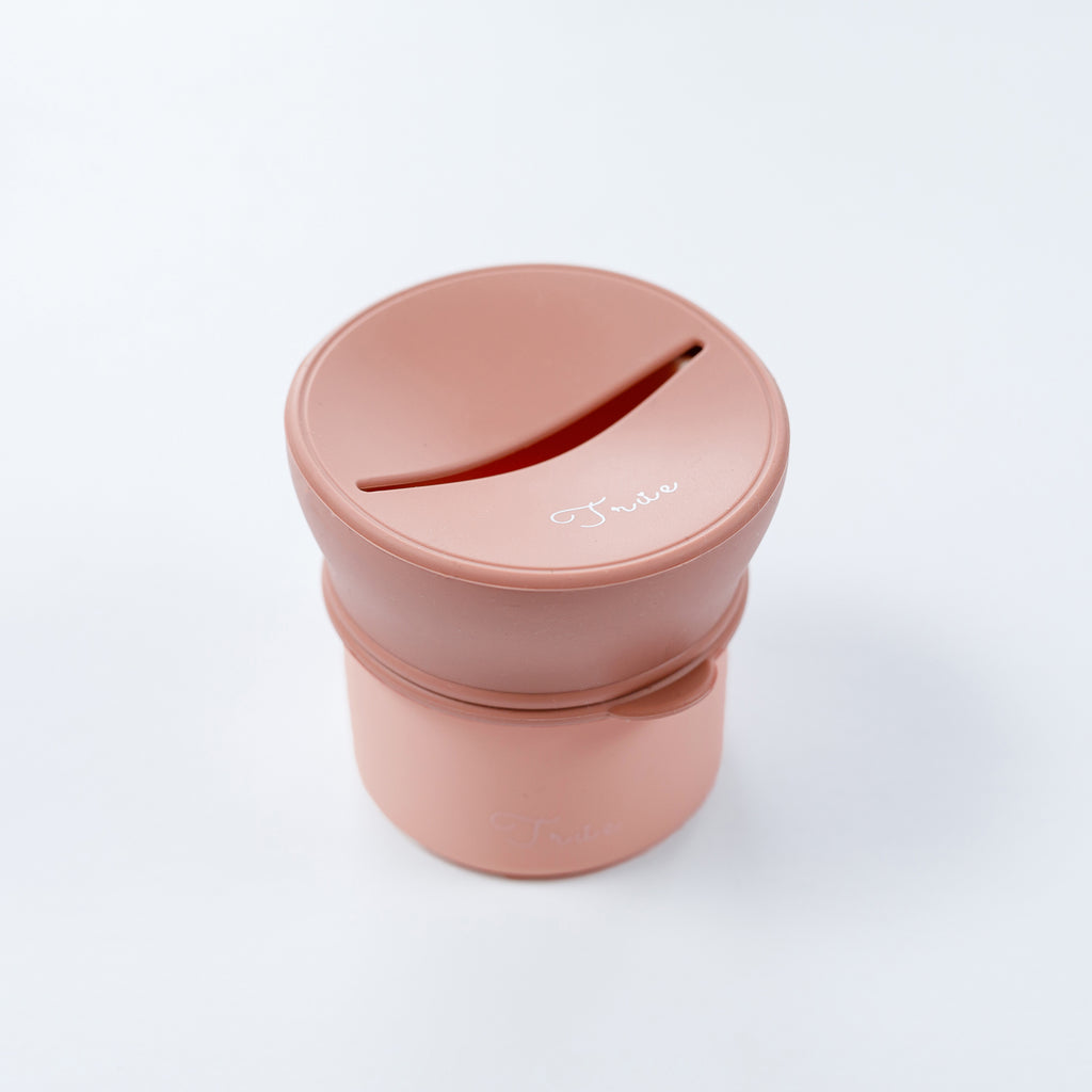 True silicone snack lid with cup in pastel pink color, BPA Free. The lid has a sliced opening in the middle.