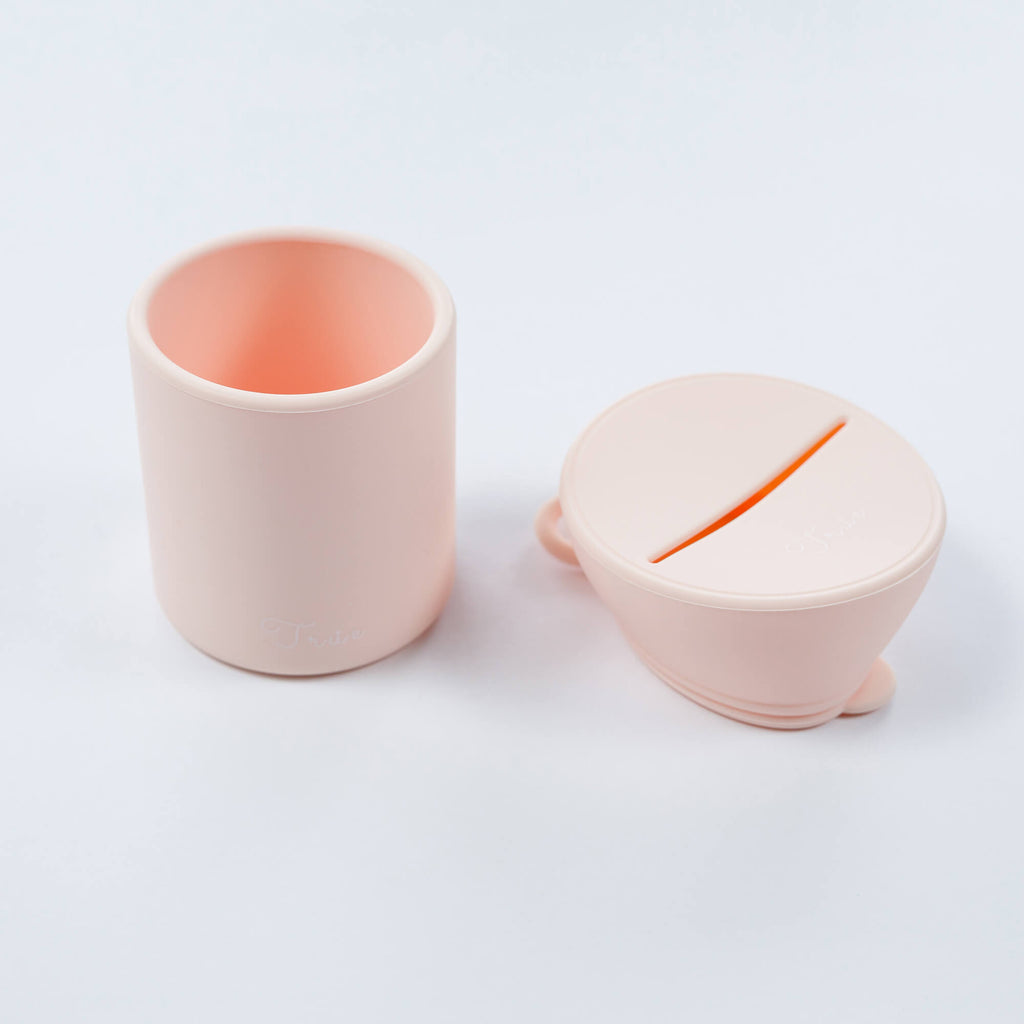 True silicone snack lid with cup in pastel pink color, BPA Free. The lid has a sliced opening in the middle.