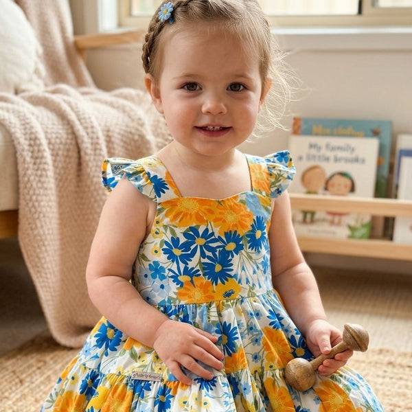 Child wearing a floral dress with blue and yellow flowers indoors.