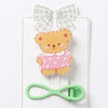 Teddy bear-shaped hair clip with a green clip on a white background