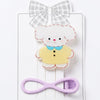 Set of hair accessories including a bow, a fluffy character clip, and a purple clip on a white background.
