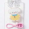Cartoon sheep hair clip with pink bow and checkered ribbon on a white background