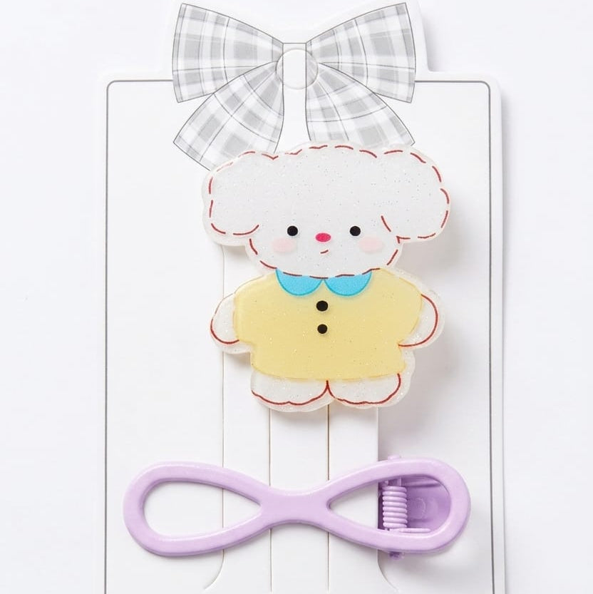 Set of hair accessories including a bow, a fluffy character clip, and a purple clip on a white background.
