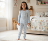 Child wearing a light blue pajama set in a bedroom