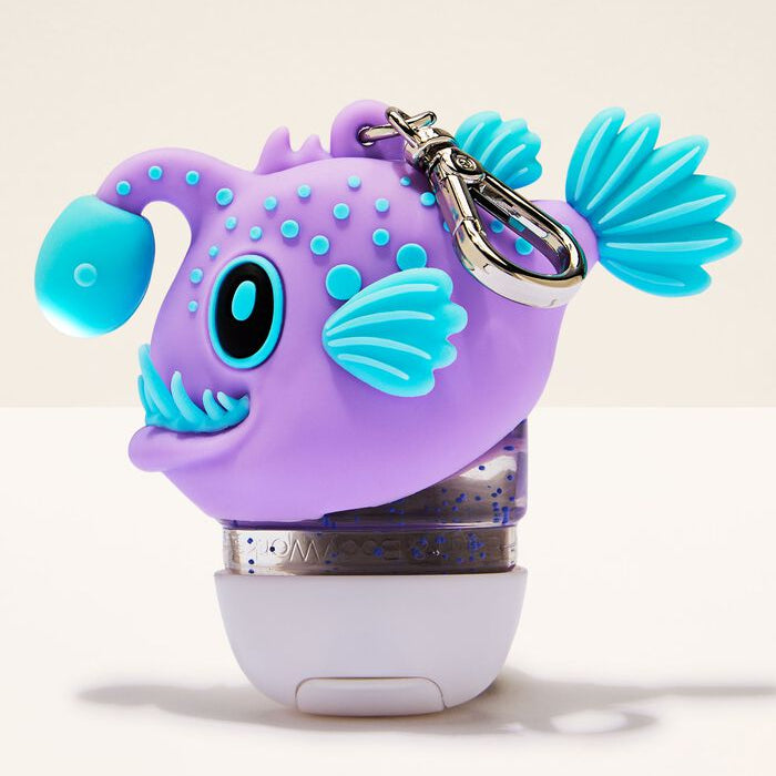 Purple and blue fish-shaped keychain with a white base on a beige background