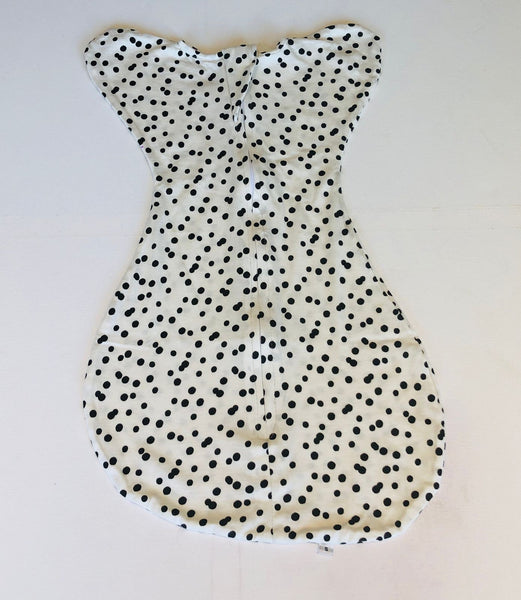 A swaddling blanket with a dalmation dog pattern in white and black colors, laid flat on a surface.