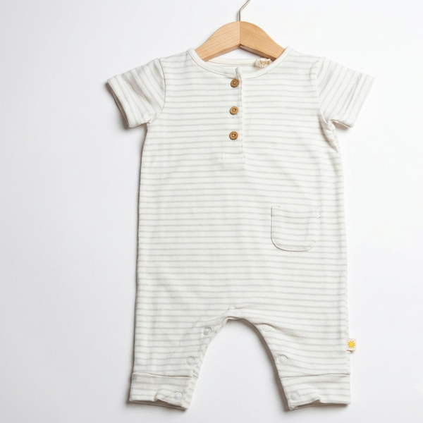 A baby romper with thin horizontal stripes in cream and light sage green, featuring a short button placket and a front pocket, hanging on a wooden hanger against a white background.