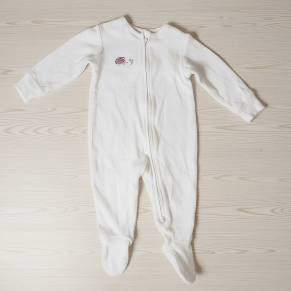 White baby onesie with a small design on a light wooden surface