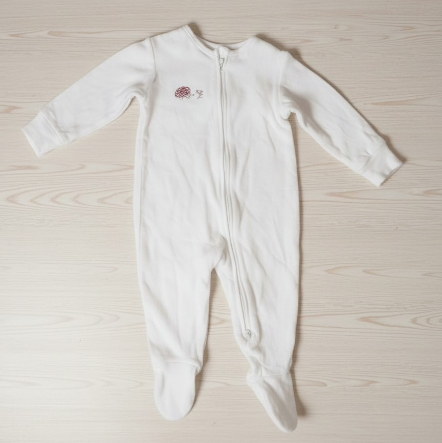 White baby onesie with a small design on a light wooden surface