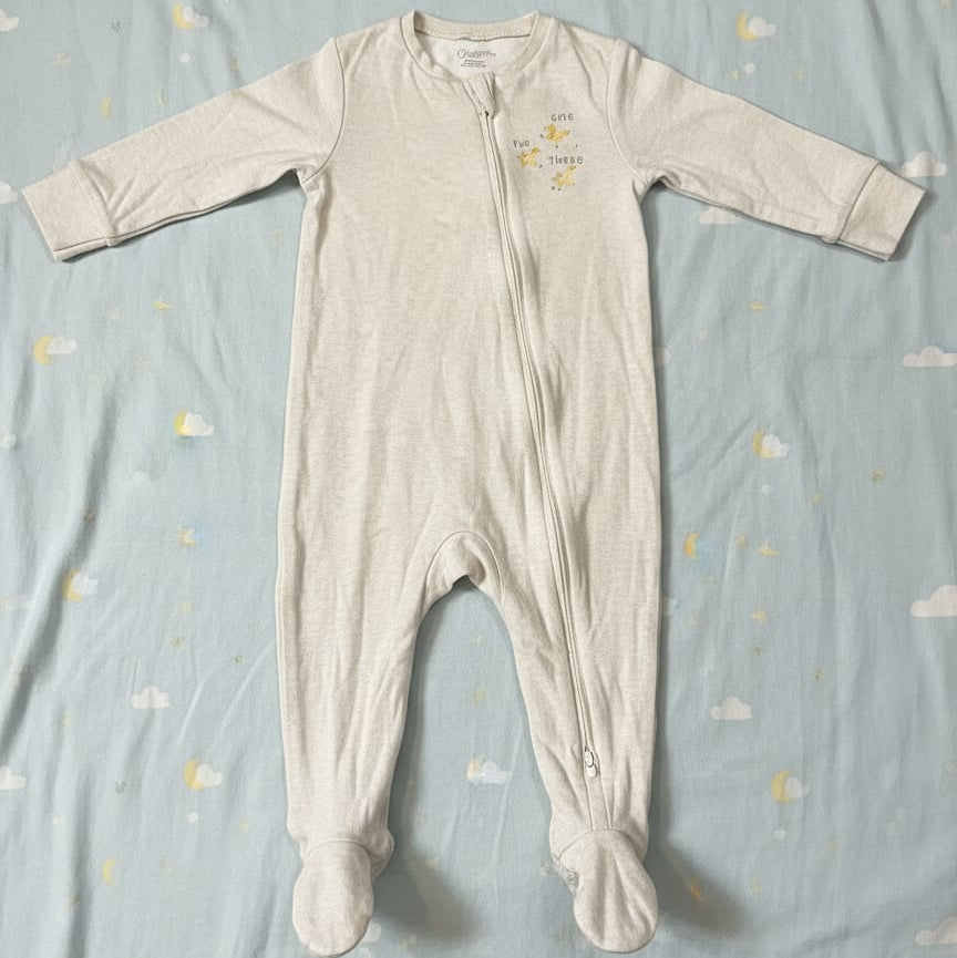 Baby onesie with footies on a blue blanket with cloud pattern