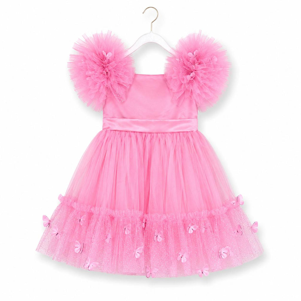 A pink toddler girl's party dress with a tiered tulle skirt and fluffy pom-pom shoulder details, hanging on a white plastic hanger against a white background.