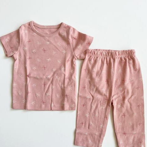 Pink children's pajama set with small patterns on a light gray background