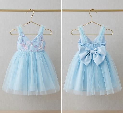 Two light blue children's dresses on hangers against a neutral background