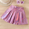 Pink metallic skirt on a wooden surface with a straw hat and flowers.
