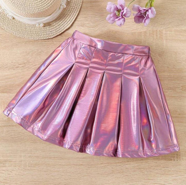 Pink metallic skirt on a wooden surface with a straw hat and flowers.