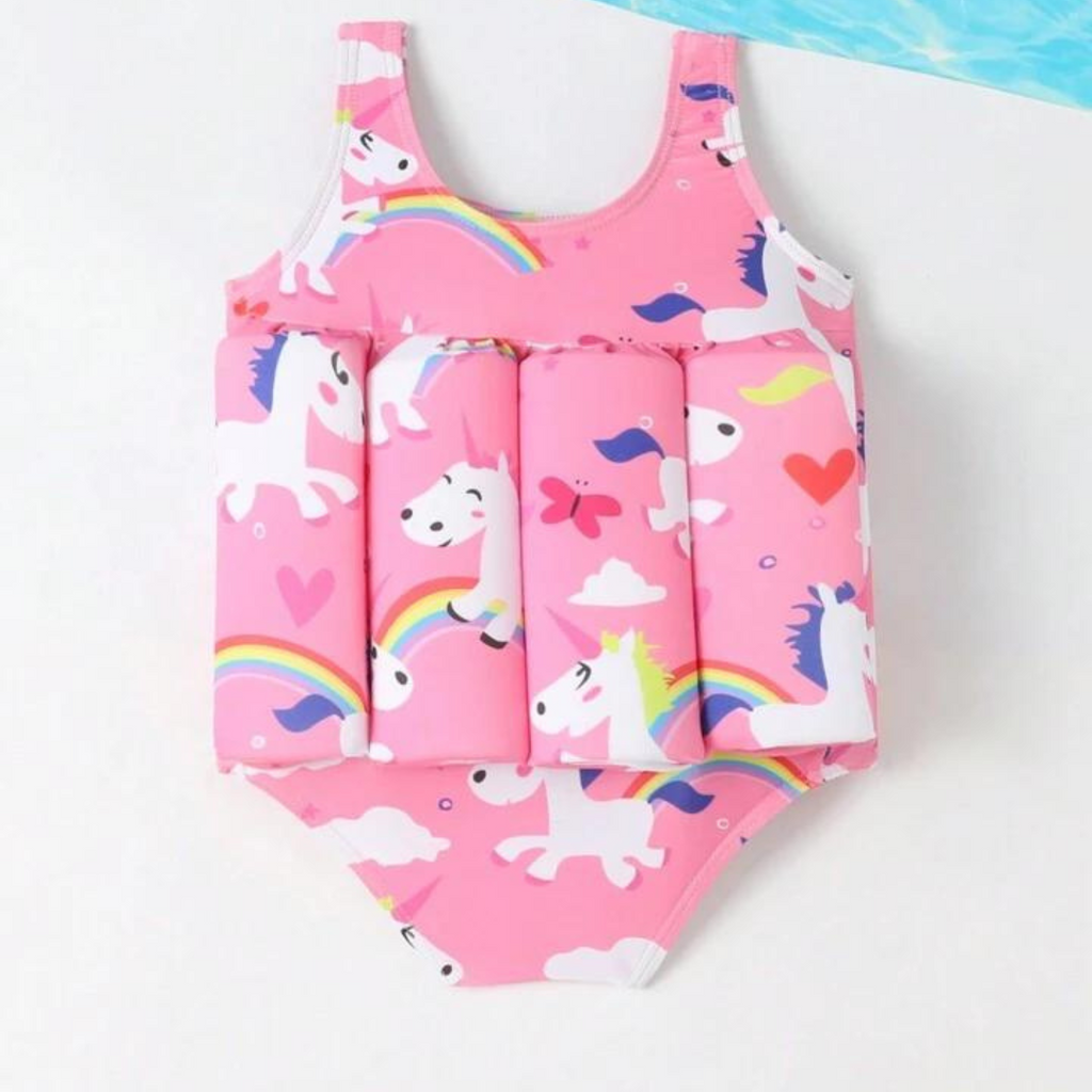 A pink one-piece swimsuit for babies with unicorn and rainbow print, featuring a frontal flotation device.