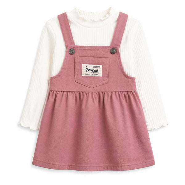 Pink denim dress with black buttons over a white long-sleeve shirt on a white background