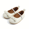 Pair of white baby shoes with brown soles on a white background