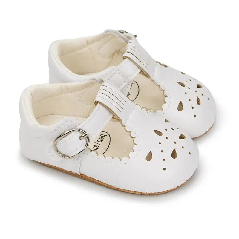White baby shoes with cut-out design on a white background