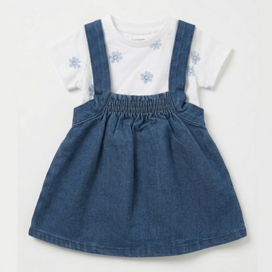 Children's outfit with blue denim pinafore and white shirt with floral design on a light gray background