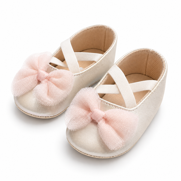 A pair of baby ballet flats in cream-colored suede with large, soft pink tulle bows on the toes, shown on a clean white background.