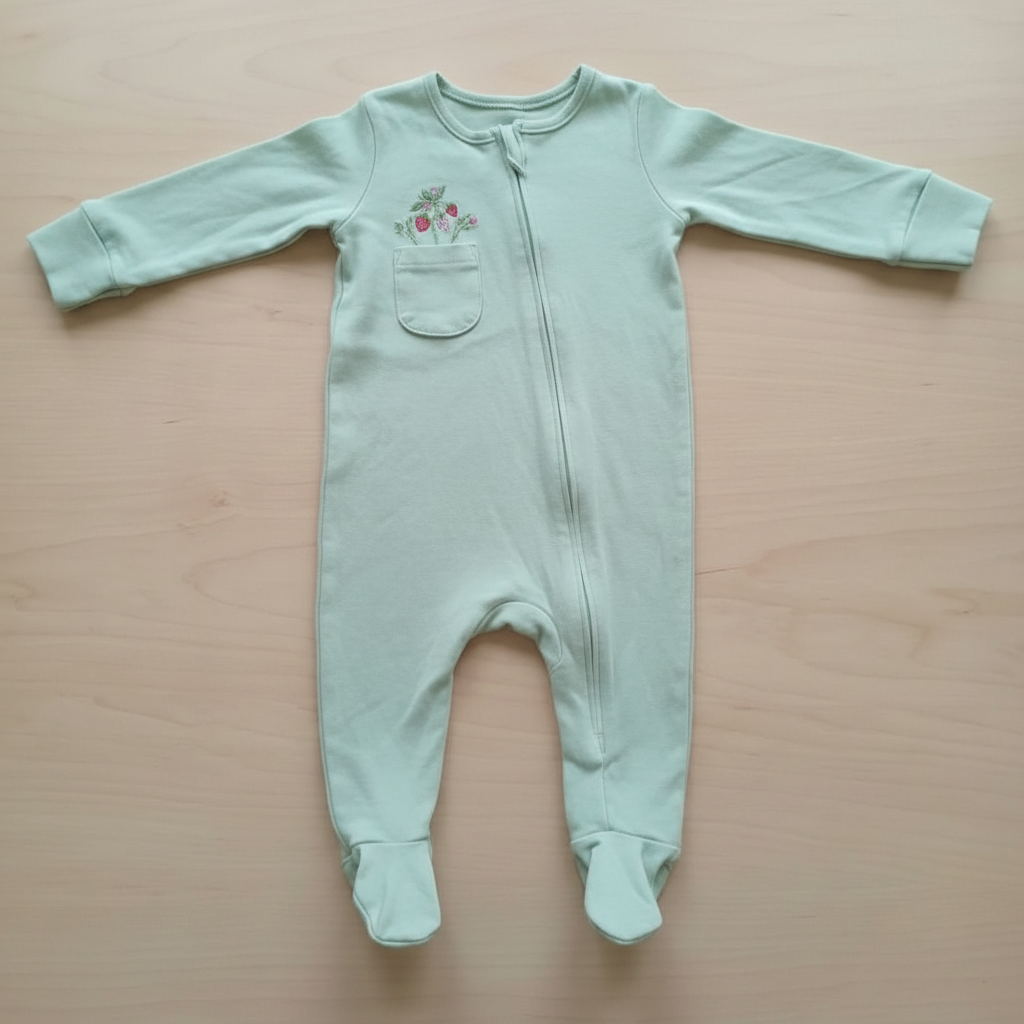 Light green baby onesie with a small design on a wooden surface