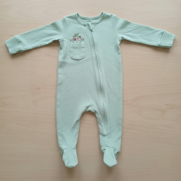 Light green baby onesie with a small design on a wooden surface