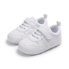 White children's sneakers with velcro straps on a white background