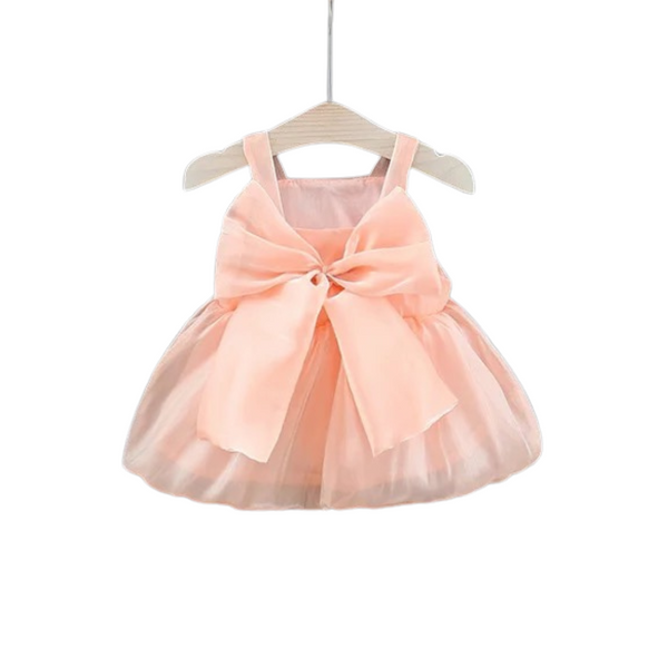 A peach-colored baby tulle party dress with a bow front on a hanger.