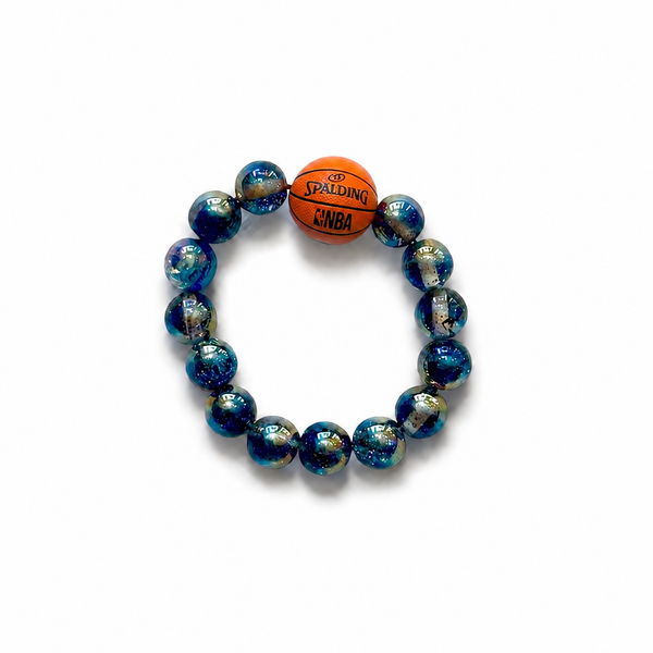 A beaded stretch bracelet featuring dark blue and black marbled glass beads with iridescent flecks, a small orange basketball charm printed with 'SPALDING' and 'NBA', on a plain white background.