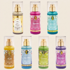 Six Disney Princess-themed room spray bottles arranged in two rows on a light beige background. The bottles feature colorful labels with gold pump dispensers and clear plastic caps, showing scents including Elsa in Frozen, Aurora, Mulan, Belle, Snow White, Tiana, and Rapunzel.