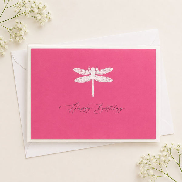 Pink birthday card with white dragonfly and 'Happy Birthday' text, surrounded by small white flowers.