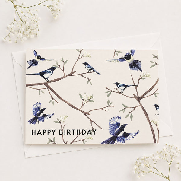 Birthday card with birds on branches and 'Happy Birthday' text, surrounded by small white flowers.