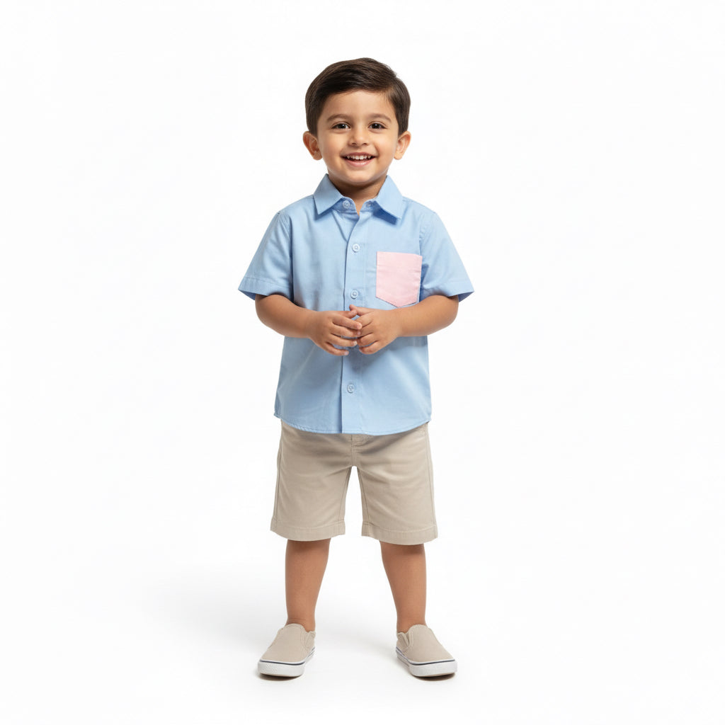 Child wearing a light blue shirt with a pink pocket and beige shorts on a white background