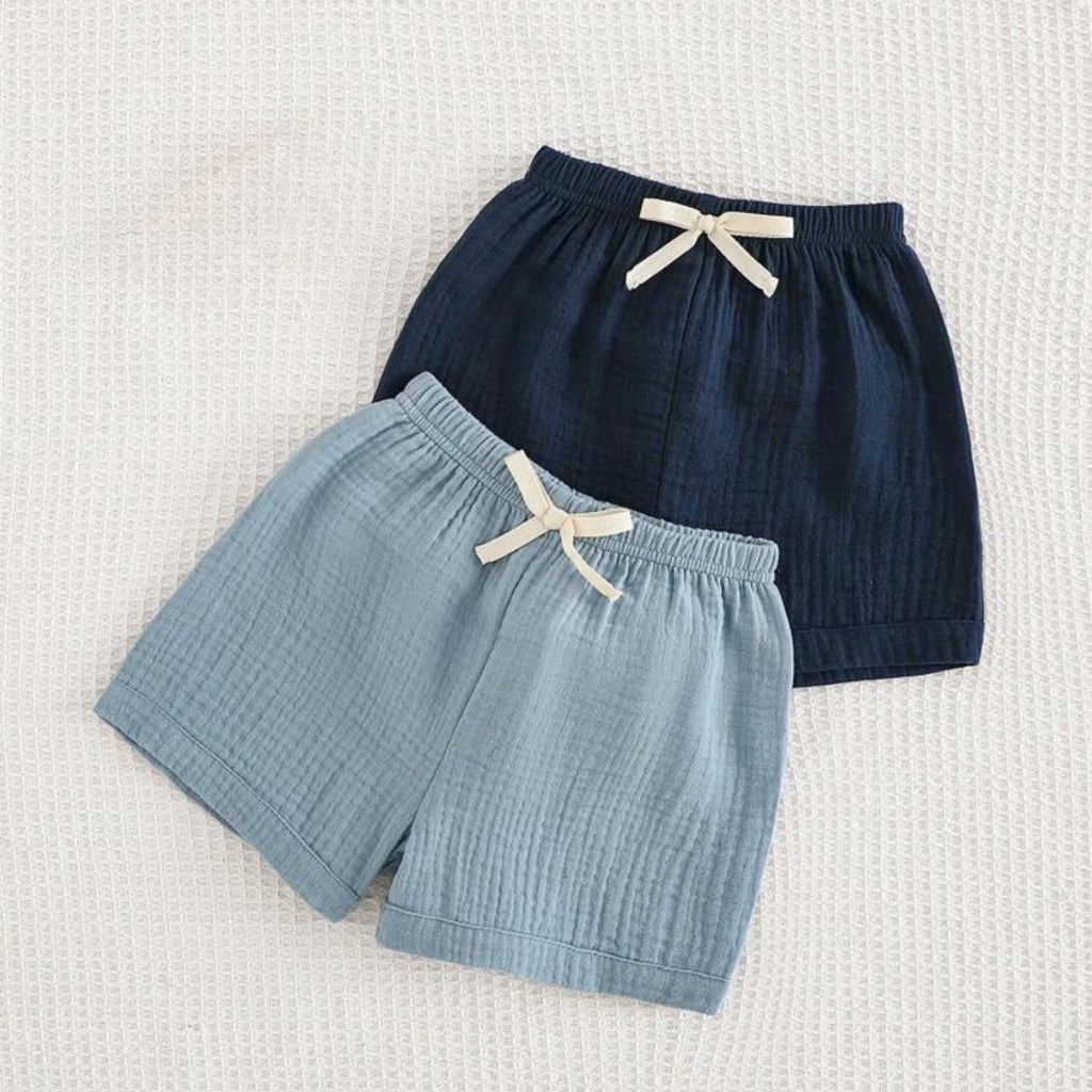 Two pairs of shorts, one blue and one navy, on a textured white background.