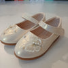 White children's shoes with decorative elements on a light background