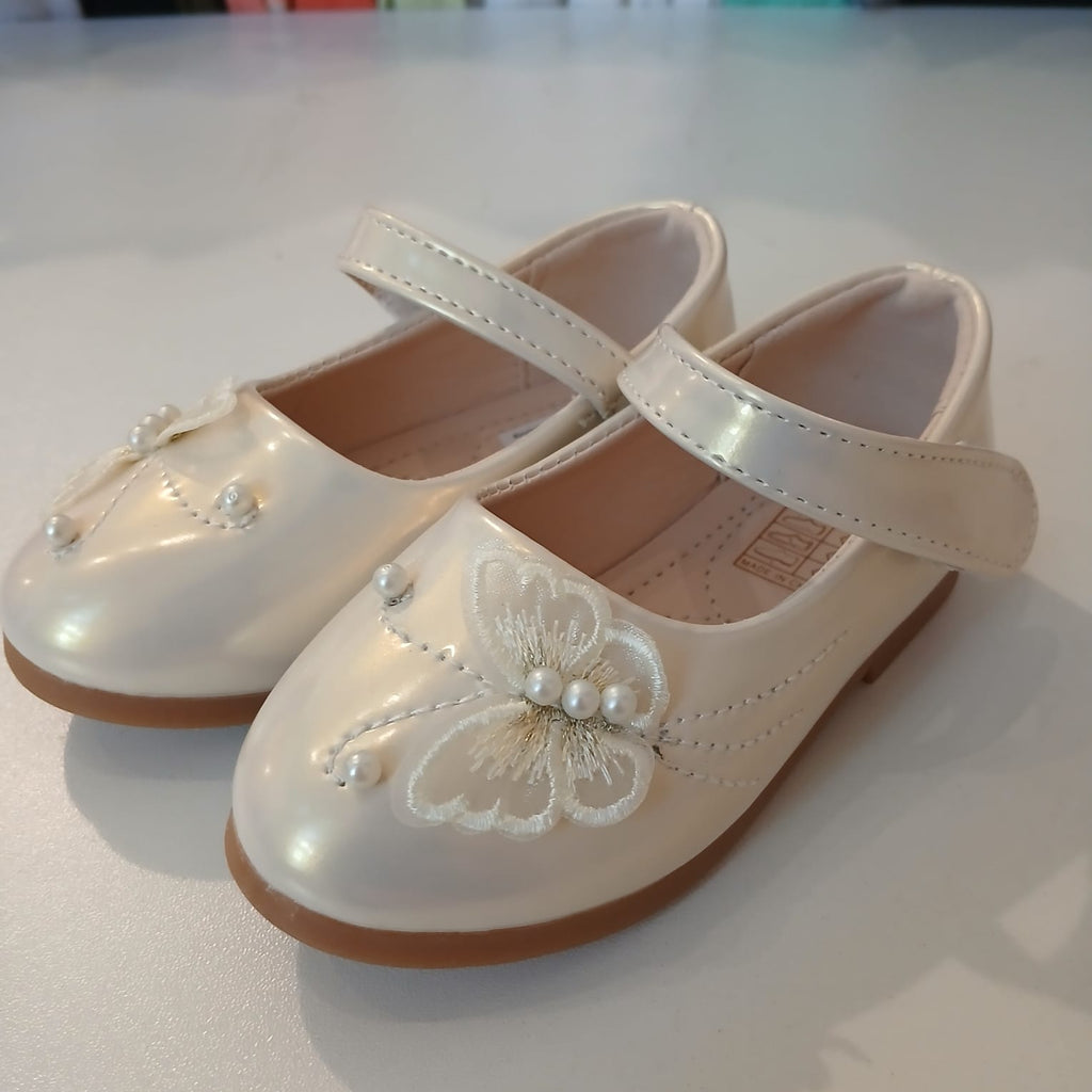 White children's shoes with decorative elements on a light background