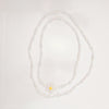 Pearl necklace with a yellow pendant on a light gray background