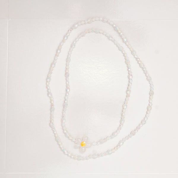 Pearl necklace with a yellow pendant on a light gray background