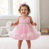 Child wearing a pink dress with a bow in a room.