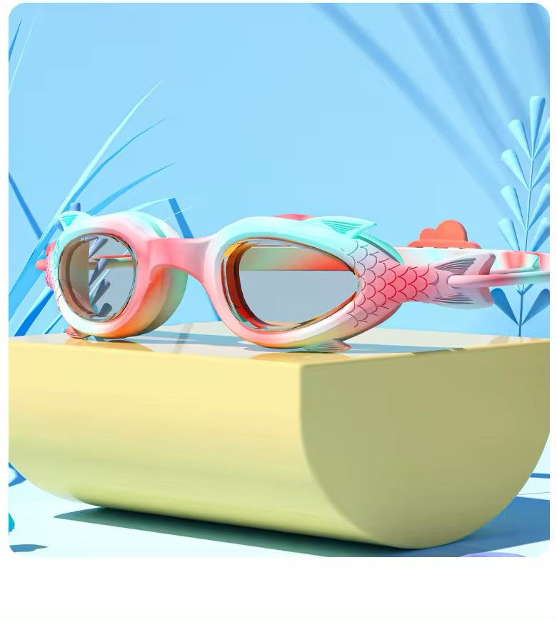 Children's swim goggles with a mermaid pink color and a design resembling a mermaid tail on the strap.
