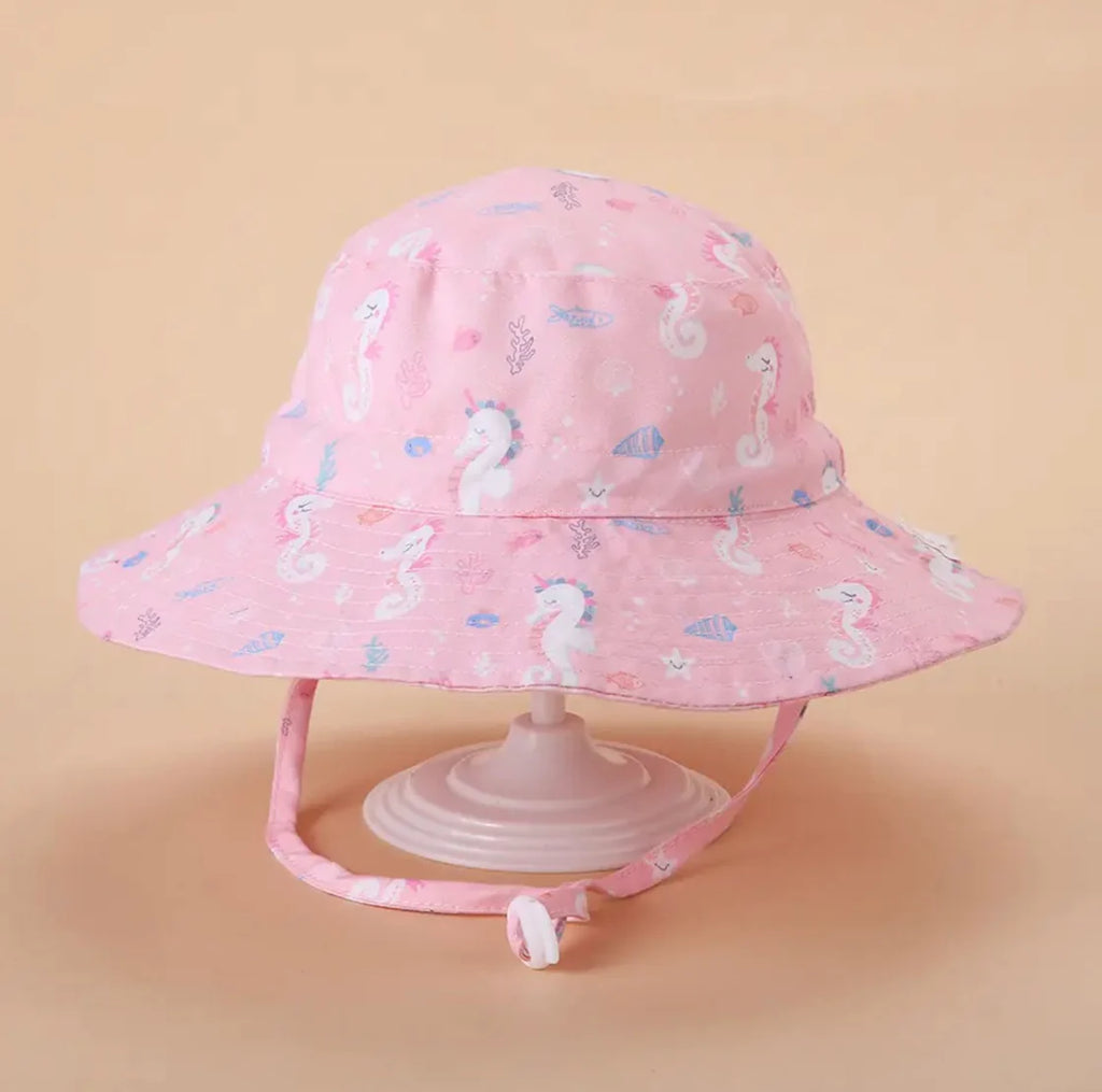 A pink children's sun hat with seahorse print displayed on a mannequin head.