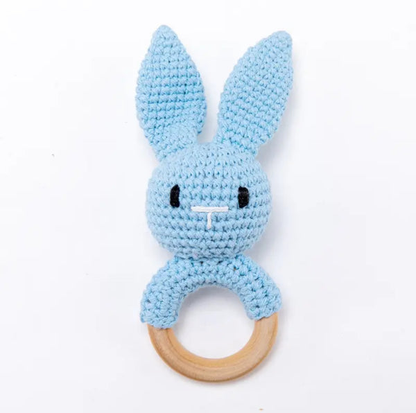 A blue crochet bunny rattle with a wooden ring attached to its body.