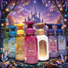 A group of Disney Princess-themed hand soap bottles arranged in front of a whimsical castle and glowing forest backdrop. The center bottle is pink and labeled Aurora, with surrounding bottles in teal, blue, gold, cream, lavender, and dark blue, each with Disney princess character artwork and pump tops.