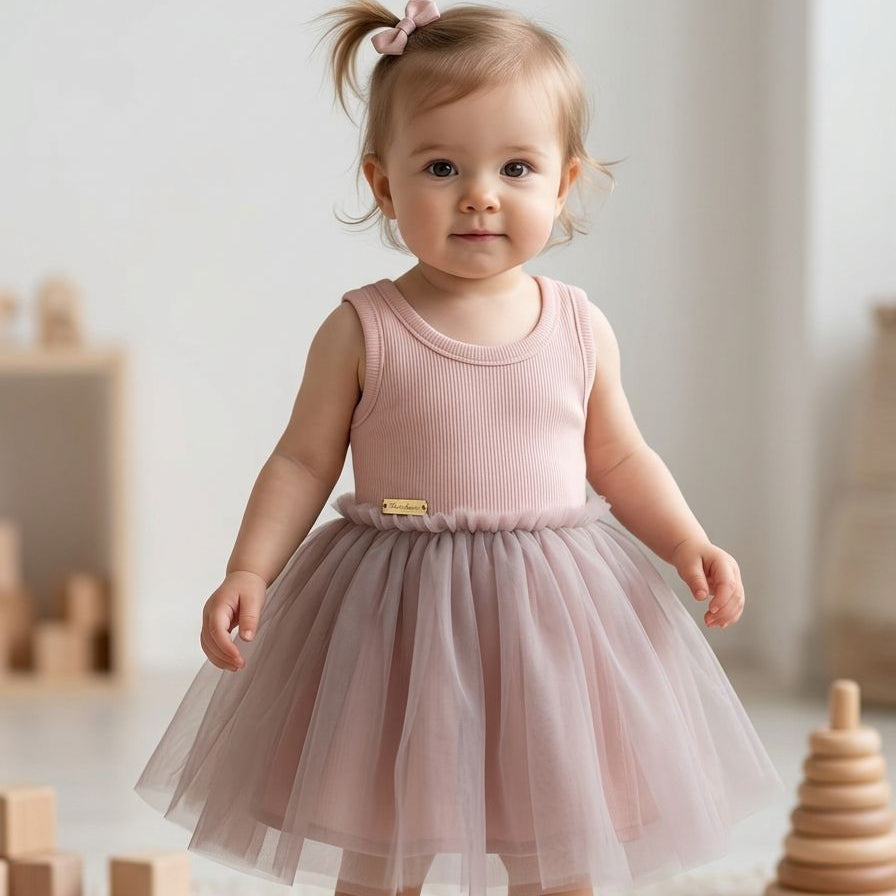 Child wearing a pink dress with a tutu skirt in a room with wooden toys.