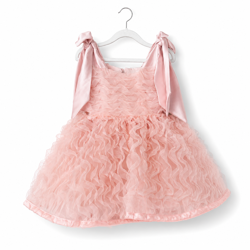 Pink dress with bow straps on a white hanger against a white background