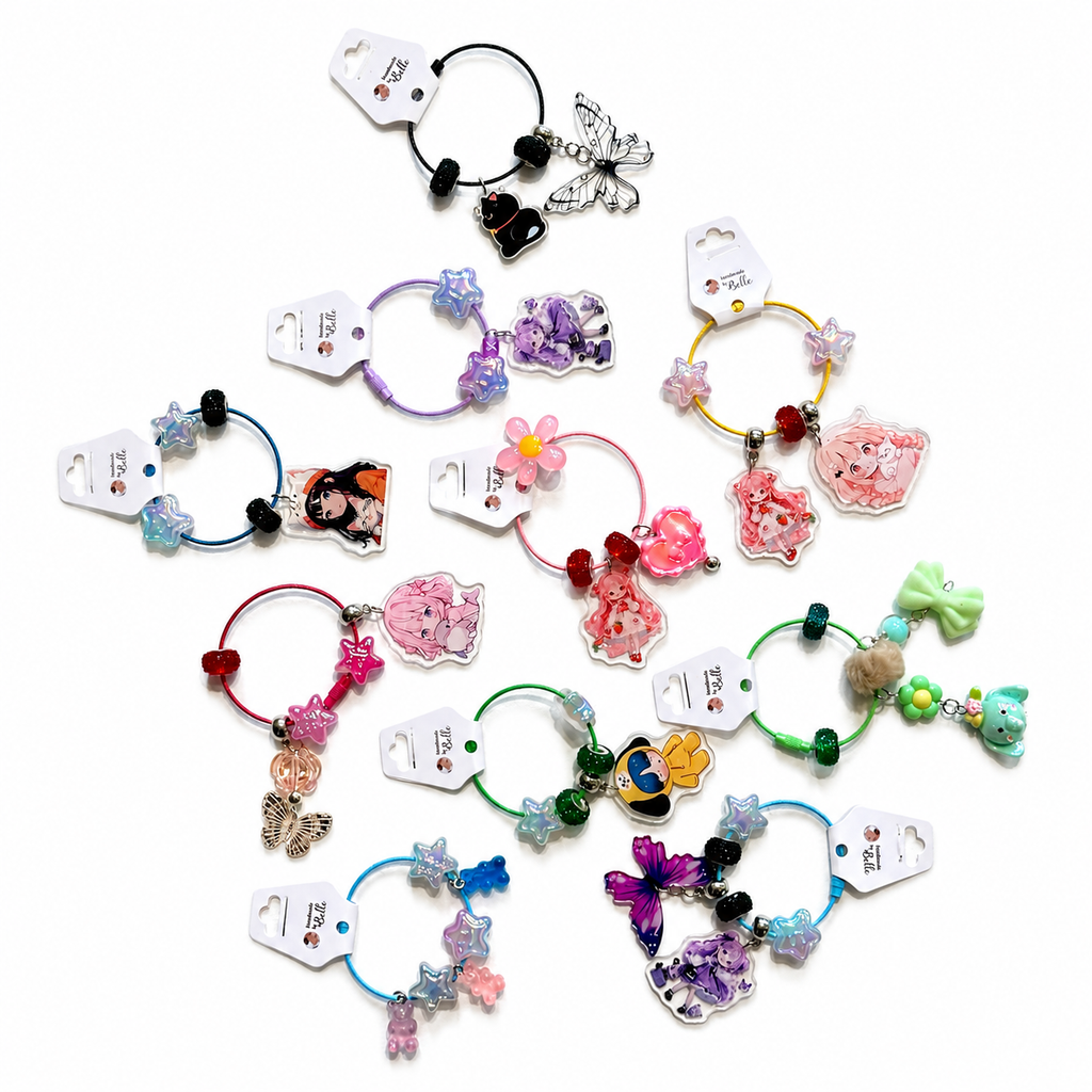 A collection of colorful hair elastic bands with various charms, displayed on a clean white background. Each band has its own unique design featuring beads, butterflies, flowers, cartoon characters, and bows, with some still attached to their white paper tags.